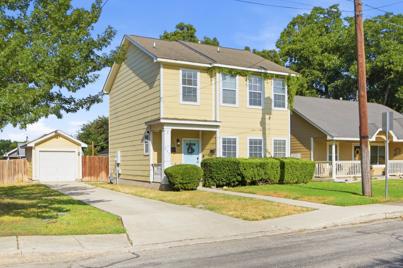 A two-story residential house with a front porch, a garage, and a well-maintained lawn.
