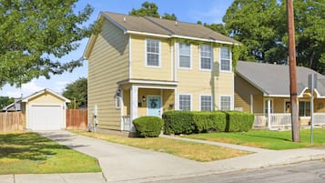 A two-story residential house with a front porch, a garage, and a well-maintained lawn.