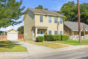 A two-story residential house with a front porch, a garage, and a well-maintained lawn. - Alamodome~Backyard Games~Grill~Near Downtown (San Antonio)