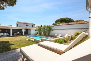 A backyard with a swimming pool, lounge chairs, and a deck. - Stunning architect-designed villa (LA COUARDE SUR MER)