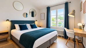 A modern bedroom with a large bed, bedside tables, a desk, and a window with curtains. - Stunning architect-designed villa (LA COUARDE SUR MER)