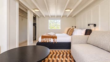Una habitación de hotel con cama, sofá, una mesa redonda y una alfombra estampada.