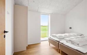 A bedroom with a bed, a bench, and a view of a green field through a window. - Stunning home in Haderslev with WiFi (Haderslev)