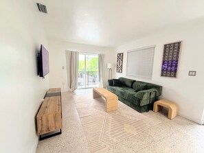 Una sala de estar moderna con un banco de madera, un sofá verde y un televisor montado en la pared.