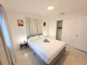 Un dormitorio con cama, mesita de noche y armario.