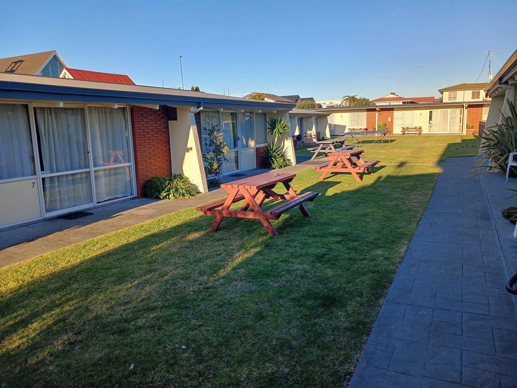 Un motel con un camino pavimentado y mesas de picnic.