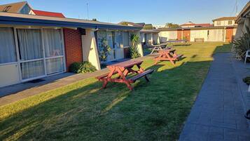 Un motel con un camino pavimentado y mesas de picnic.