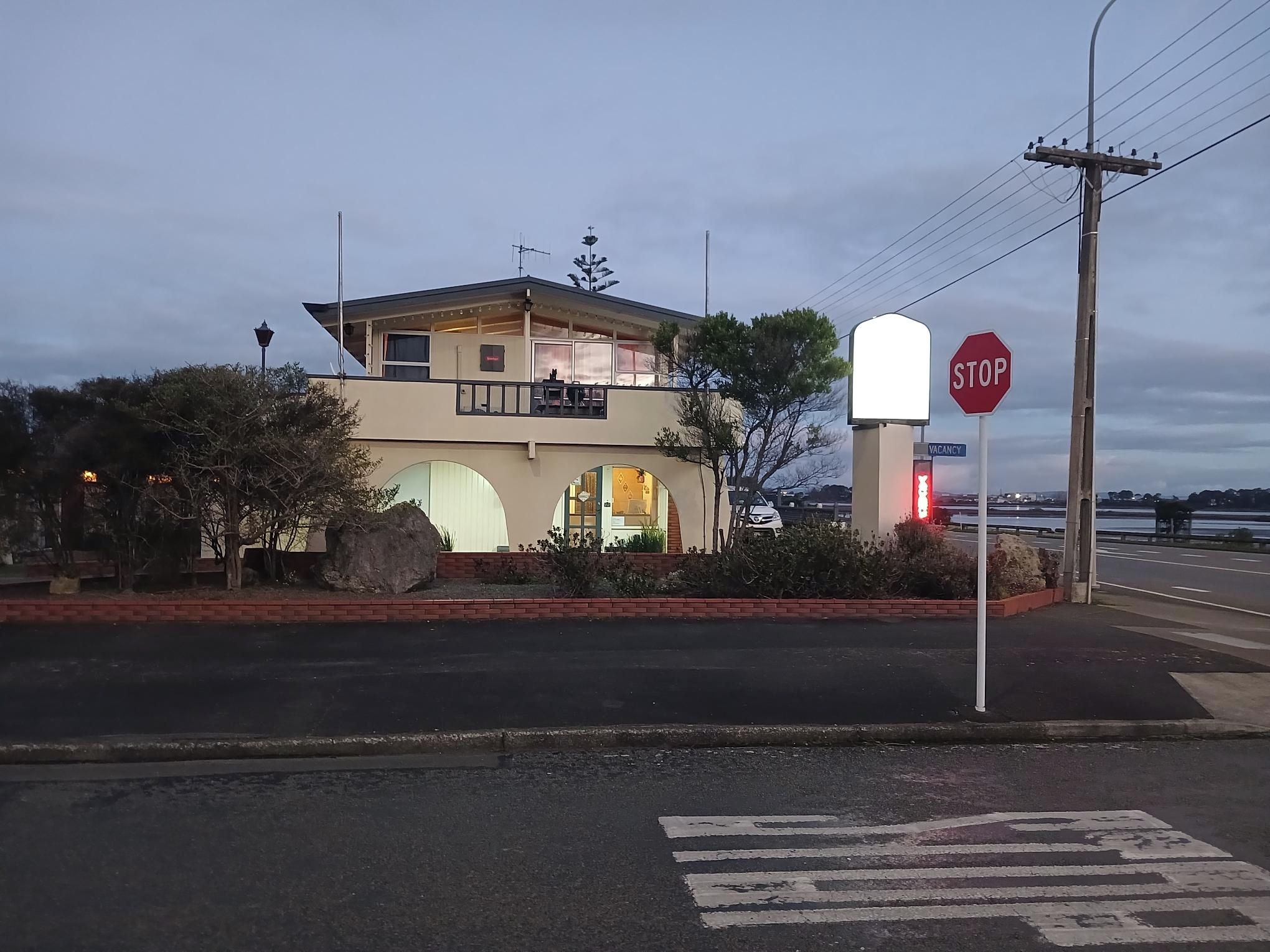 Un edificio de dos pisos con un balcón, una señal de stop y un cartel de 'No Vacantes'.