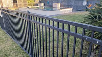 Un patio trasero cercado con piscina, un cobertizo y un árbol.