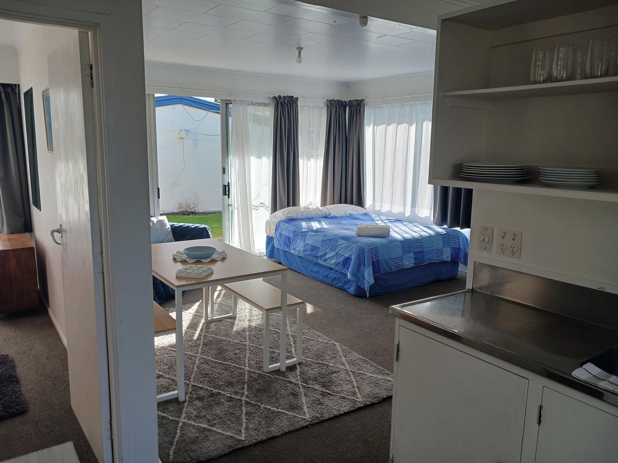 A compact room with a bed, a small table, and a kitchenette.