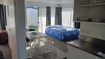 A compact room with a bed, a small table, and a kitchenette.