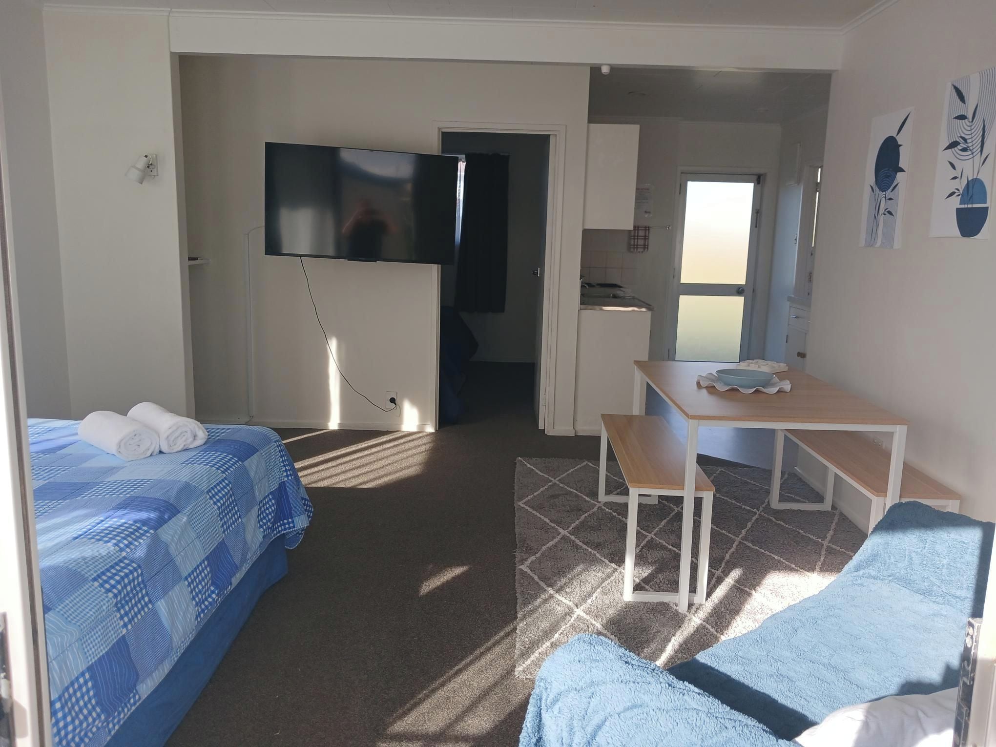 Quarto de hotel com cama, escrivaninha, cadeira, televisão e vista para o exterior.