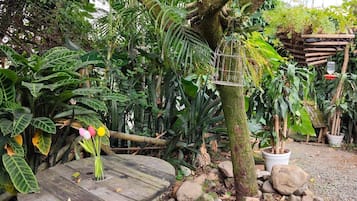 Un jardín con un banco de madera, una mesa de piedra y diversas plantas.