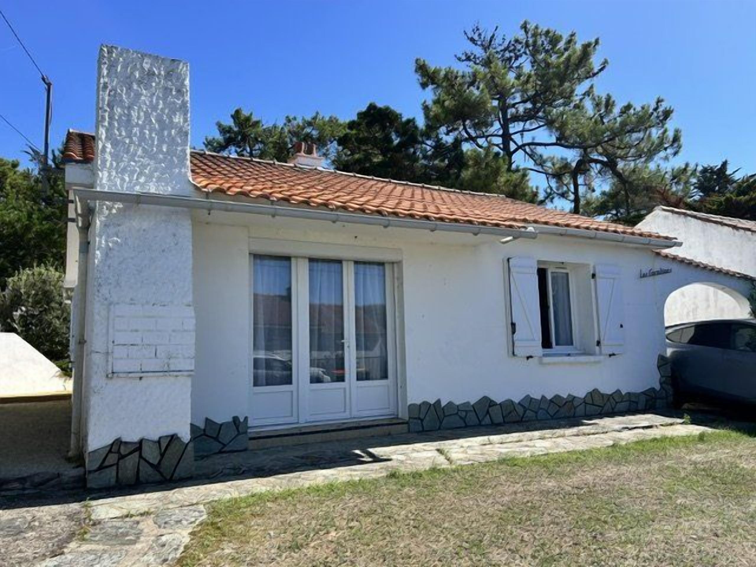 Un bâtiment d’un seul étage, doté d’un toit recouvert de tuiles, d’une façade blanche et de fondations en pierre.
