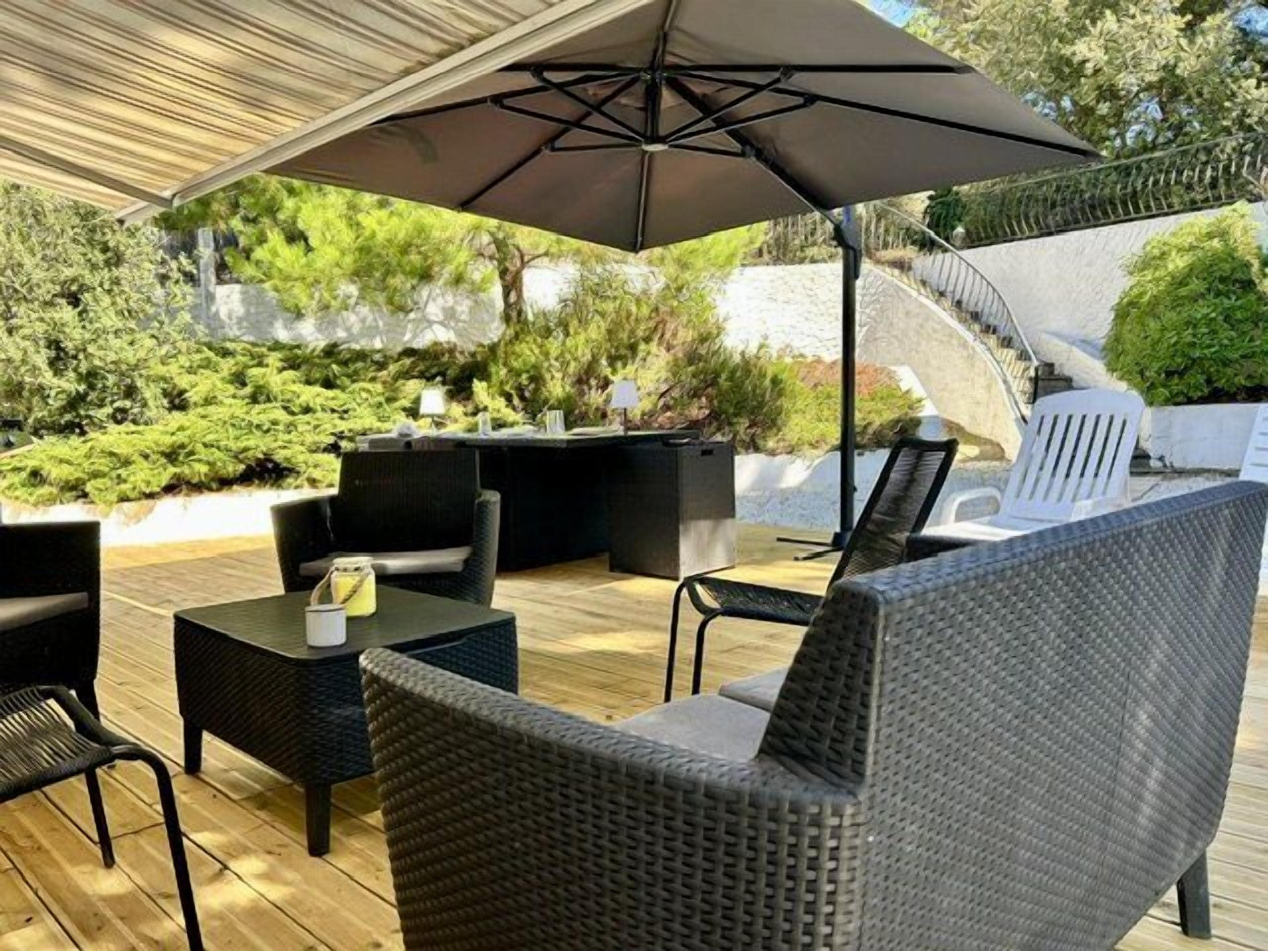 An outdoor patio with wicker furniture, a table, and a large umbrella.