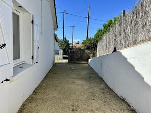 A narrow outdoor area with a white wall and a wooden fence. - Les Carolines de Sion (SAINT HILAIRE DE RIEZ)