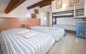 Ein Zimmer mit zwei Betten, einem hölzernen Kopfteil, einem kleinen Tisch und einem Schlafsofa.