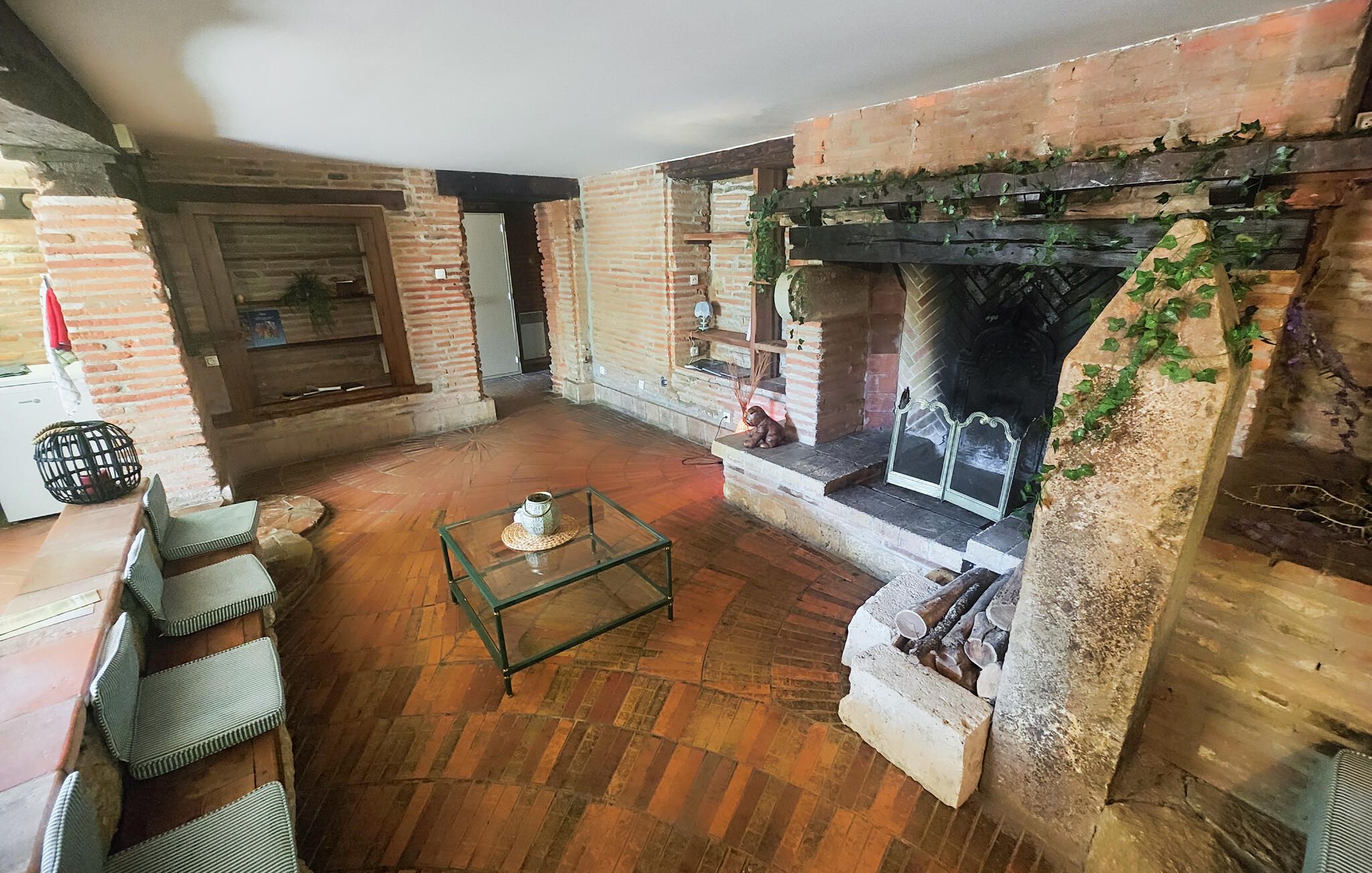 Una habitación acogedora con una chimenea de ladrillo, una mesa de centro de vidrio y un rincón de descanso con sillones mullidos.