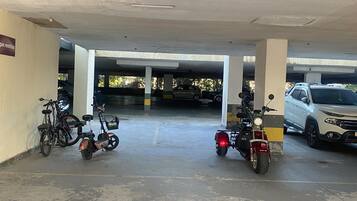 A parking garage with concrete pillars, a blue line marking, and vehicles including a motorcycle and a car.