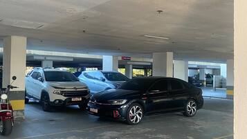 Um estacionamento com vários carros estacionados, incluindo um SUV branco e um sedan preto.