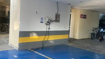A parking garage with blue painted parking spaces, a wall-mounted electrical box, and a sign reading 'Vagas reservas'.