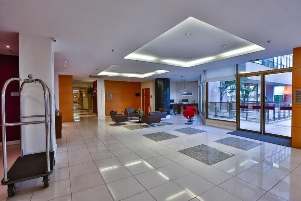 A hotel lobby with a reception desk, seating area, and a large glass door leading outside.