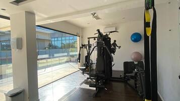 Academia com equipamentos de ginástica, uma grande janela e vista para o exterior.