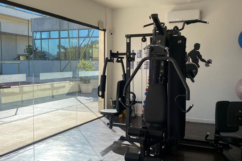 A gym with a variety of exercise equipment, including a squat rack and weight benches.
