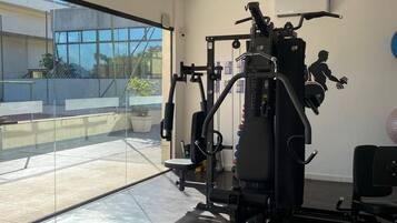 A gym with a variety of exercise equipment, including a squat rack and weight benches.
