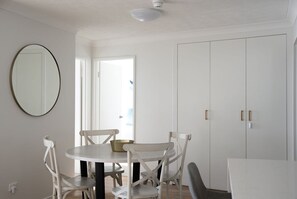 A room with a round table, four chairs, a large mirror, and a wardrobe with two doors. - Ocean Front Escape on Palm Beach (Gold Coast)