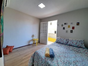 Un dormitorio con una cama, una mesita y una puerta que da a un espacio exterior.