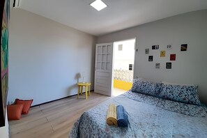 A bedroom with a bed, a small table, and a door leading to another room. - Porto de Galinhas Maraca 100mMar Loctemp (Ipojuca)