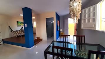A modern interior with a dining area featuring a glass table and chairs, a chandelier, and a view of a building outside.