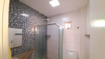 Een badkamer met douche, toilet en wastafel.