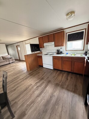A compact kitchen with wooden cabinets, a white stove, and a window above the sink. - Lovely Per Diem (Angleton)