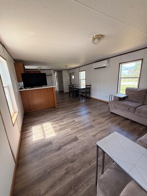 A spacious living area with a kitchen, dining table, and a sofa. - Lovely Per Diem (Angleton)