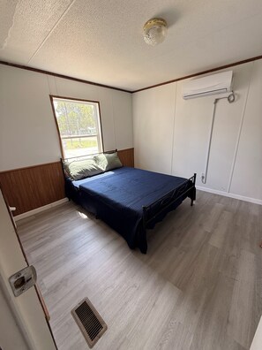 A bedroom with a bed, a window, a radiator, and a door. - Lovely Per Diem (Angleton)