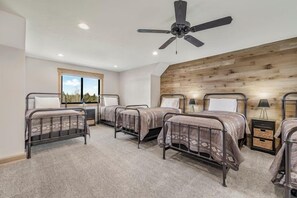 Un dormitorio con cuatro literas metálicas, un ventilador de techo y una pared de acento de madera.
