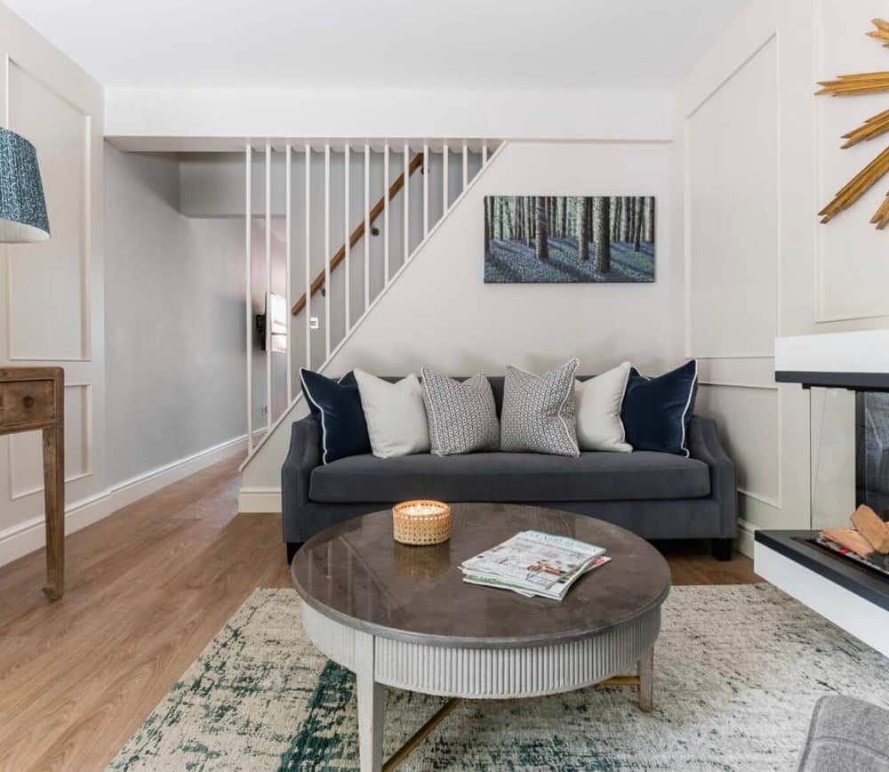 A living room with a sofa, a coffee table, a fireplace, and a staircase.
