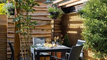 Eine Außenpatio mit einer Holz-Pergola, einem Tisch mit Stühlen und einem Blumentopf.
