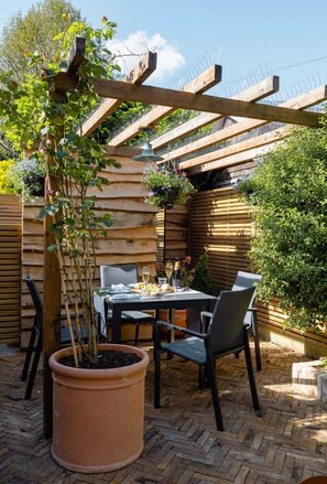 Eine Außenpatio mit einer Holz-Pergola, einem Tisch mit Stühlen und einem Blumentopf.