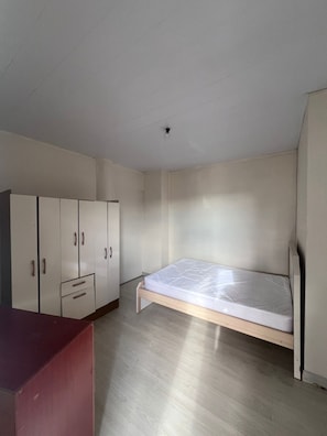A room with a bed, a wardrobe, and a desk.