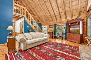 A wooden interior with a sofa, patterned rug, and a television. - Chestnut Bearcation - Pet-Friendly, Screened Porch, Game Room, Wood-Burning Fireplace & More! (Blue Ridge)