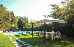 A backyard with a swimming pool, lounge chairs, a covered patio table, and a stone pathway. - 1 bedroom amazing home in Poggibonsi (Poggibonsi)