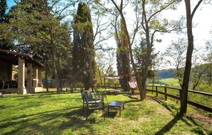 An outdoor seating area with chairs and a table, surrounded by trees and a view of the countryside. - 1 bedroom amazing home in Poggibonsi (Poggibonsi)