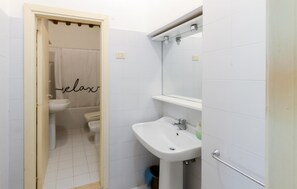 Ein Badezimmer mit Toilette, Waschbecken und Duschbereich.