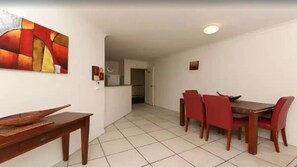A dining area with a wooden table and red chairs, a painting on the wall, and a tiled floor. - Grand Florida at Miami Beach (Gold Coast)