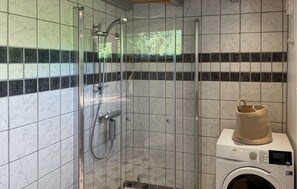 Ein Badezimmer mit Duschkabine, Waschmaschine und Handtuchhalter.