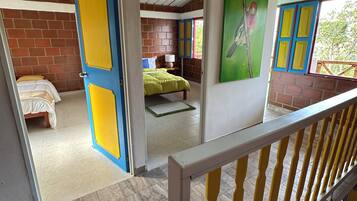 Een kamer met een bed, een raam met blauwe luiken en een groene wand.
