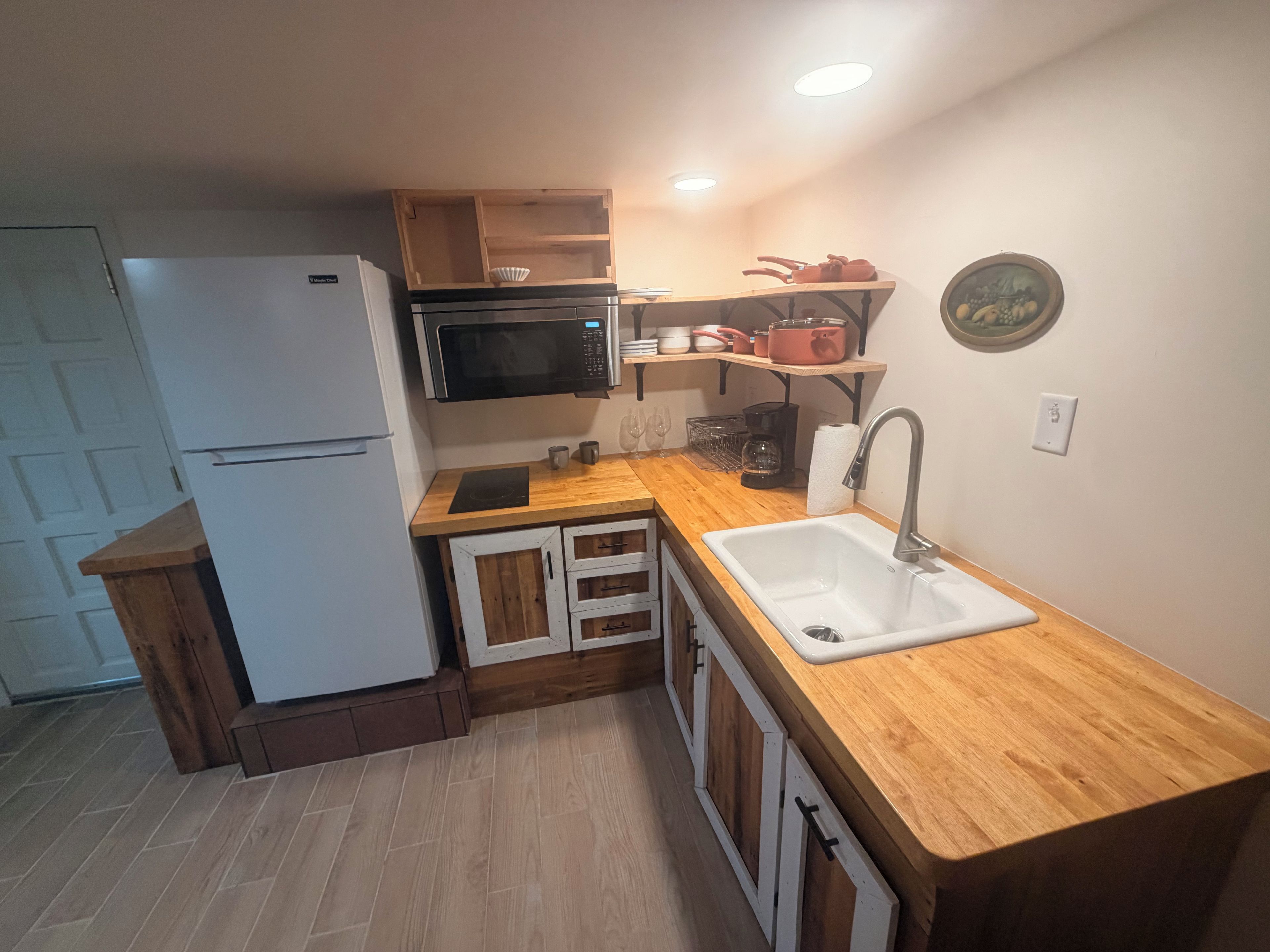 A compact kitchen with a microwave, sink, and wooden cabinets.